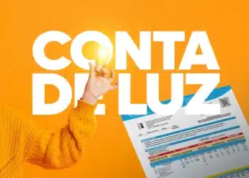 Pessoa segurando uma lâmpada enquanto mostra a fatura de energia elétrica, simbolizando a mudança no sistema de faturas.