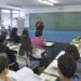 Professor de inglês dá aula para turma de adolescentes em sala de aula com estudantes atentos.
