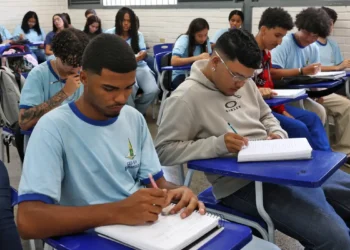 Alunos em sala de aula escrevendo em cadernos, foco no ensino em 2026