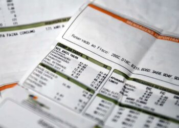 Close em duas faturas de energia elétrica impressas em papel branco, com detalhes em verde e laranja. O foco está nos campos de "Composição da Tarifa", "Impostos" e "Indicadores de Continuidade", mostrando os valores e taxas detalhados.