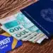 Carteira de trabalho, cédulas de 100 reais e cartão do PIS/PASEP sobre uma mesa, relacionados ao tema de ressarcimento de cotas do PIS/PASEP.