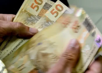 Notas de 50 reais sendo contadas, simbolizando o salário mínimo de 2026.