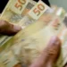 Notas de 50 reais sendo contadas, simbolizando o salário mínimo de 2026.