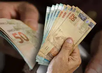 Dinheiro brasileiro em mãos, representando o impacto da desvalorização monetária na Venezuela.