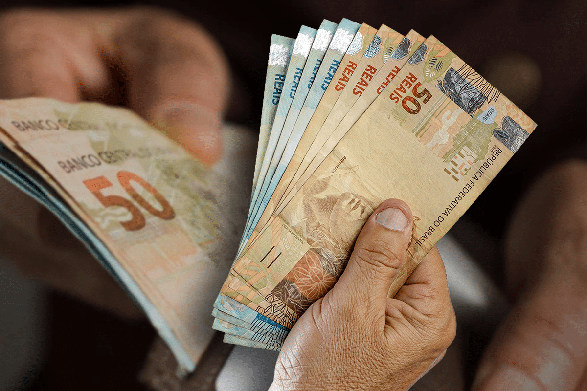 Pessoa segurando cédulas de R$50 e R$100, representando a relação entre salário e aposentadoria.