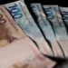 Notas de 100 e 200 reais do Brasil com fundo escuro, representando valores do programa Pé-de-Meia em 2026.