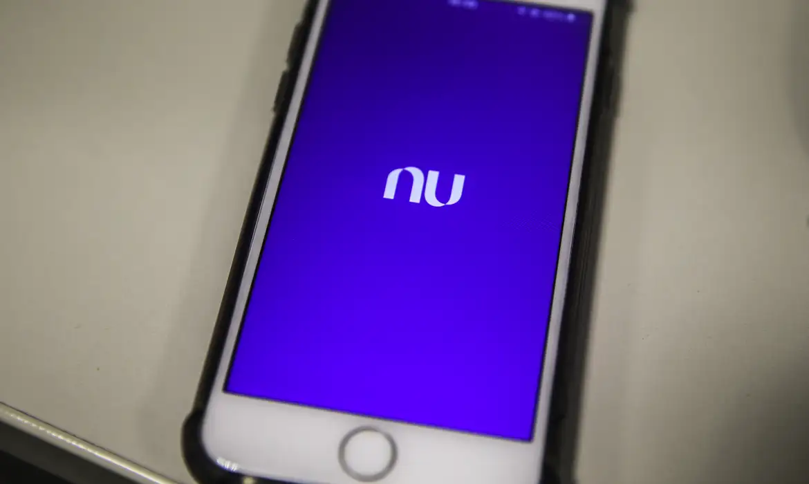 Tela inicial do aplicativo Nubank em smartphone moderno Smartphone exibe tela roxa com logotipo do Nubank no centro