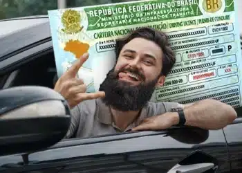 Homem sorrindo dentro do carro comemora ao segurar documento da CNH após conseguir vaga gratuita