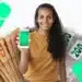 Mulher segurando celular com PIX e notas de dinheiro representando consulta de valores esquecidos em bancos para recebimento em 2026