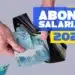 Mãos segurando carteira preta aberta com notas de R$ 100 e texto Abono Salarial 2026 ao lado.