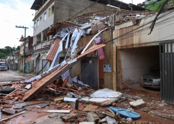 Casa destruída com telhado desabado e escombros espalhados pela rua após enchentes na Zona da Mata mineira; Caixa libera saque de até R$ 6.220 do FGTS para moradores afetados.