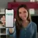 Mulher sorrindo ao segurar seu celular na tela inicial do aplicativo do FGTS.