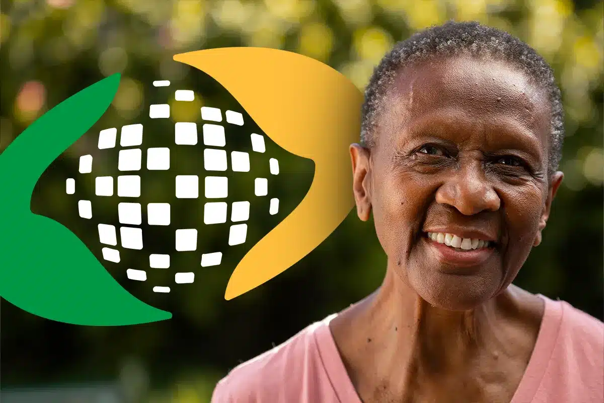 Idosa sorrindo com símbolo do INSS ao fundo sobre o calendário do 13º de 2026 Mulher idosa sorrindo em meio à natureza com logomarca do INSS em destaque