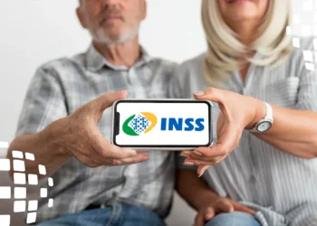 Casal segurando smartphone com logo do INSS, ambos sentados e sorrindo