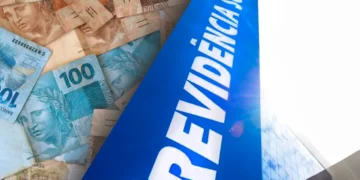 Notas de real espalhadas ao lado de placa azul com escrita Previdência Social.