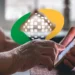 Mãos de idosa utilizando smartphone com logo do INSS sobreposto na tela