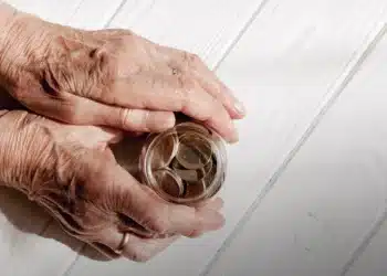 Idosa segurando pote de moedas.