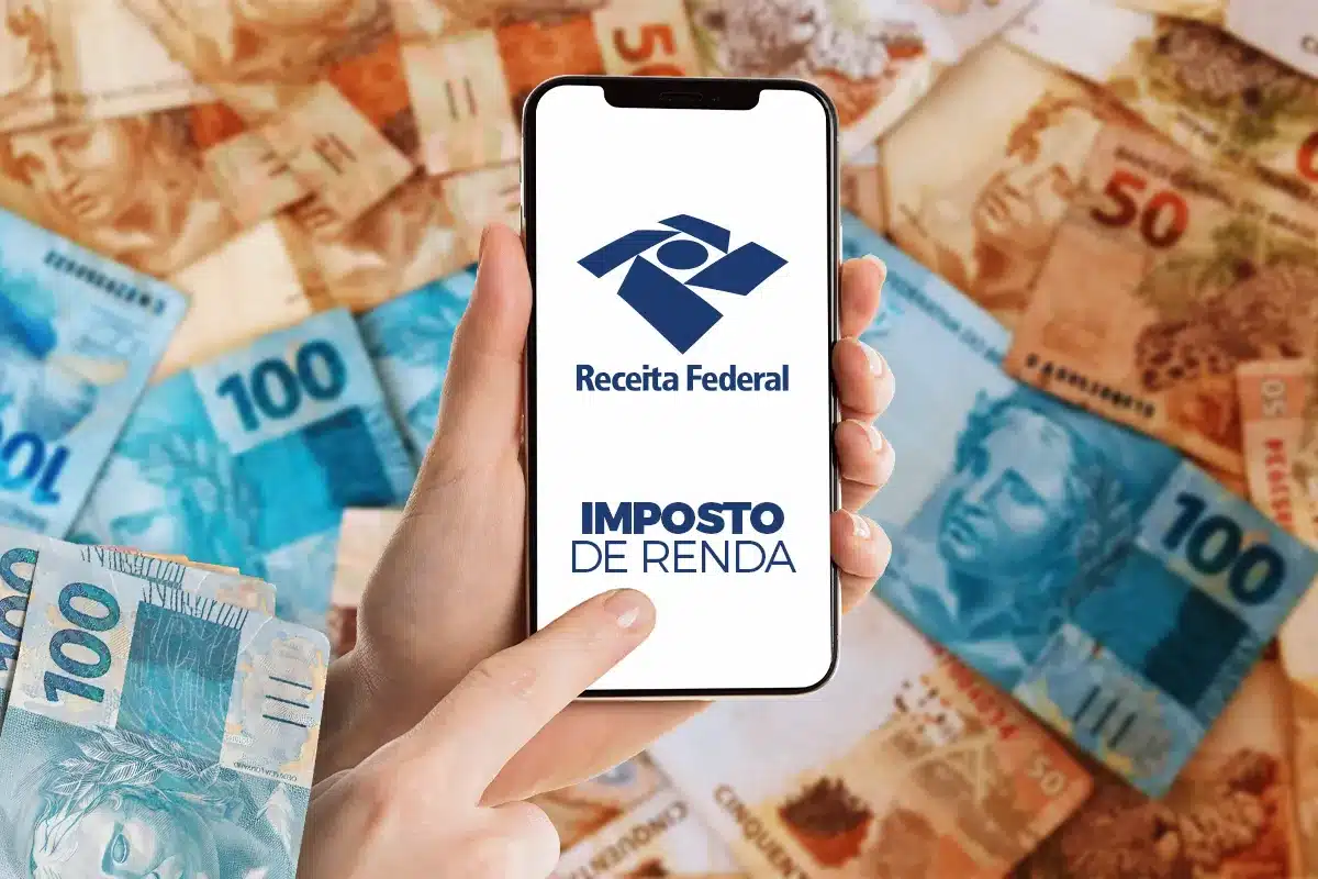 Receita Federal. Mão segura celular com logo da Receita Federal e texto "Imposto de Renda" sobre notas de real espalhadas.