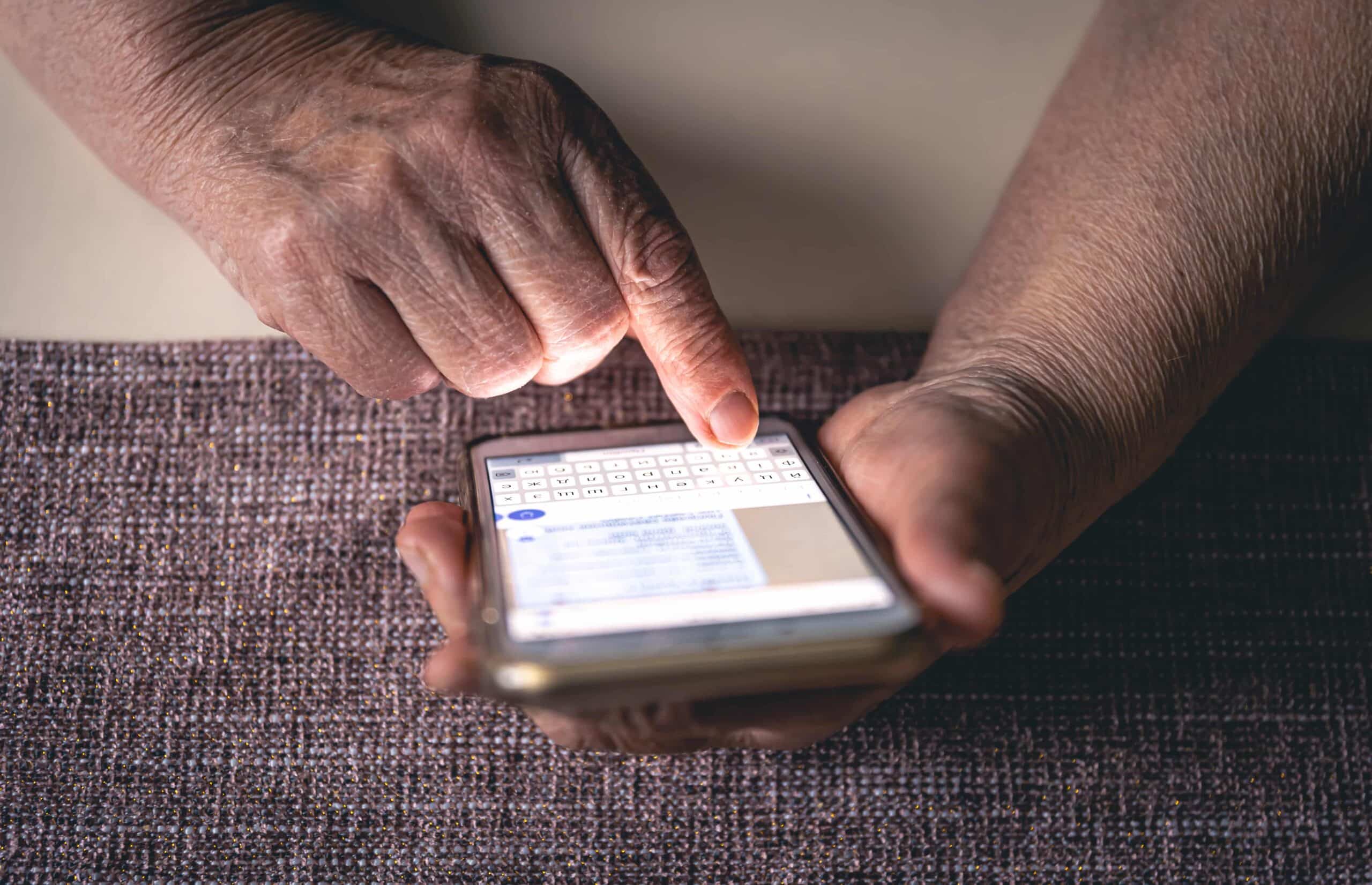 Mãos de pessoa digitando no smartphone com teclado virtual aberto