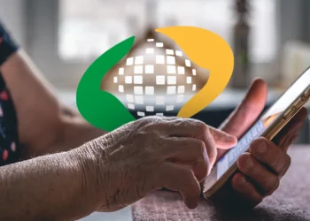 Mãos de idosa utilizando smartphone com o logotipo do INSS em destaque para consultar o calendário de pagamento do 13º salário