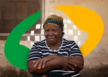 Mulher idosa de lenço estampado cruza os braços sentada, parede simples ao fundo e elementos gráficos coloridos