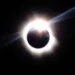 Fotografia de eclipse solar total com a coroa solar visível ao redor da Lua em fundo escuro, ilustrando o fenômeno astronômico previsto para 2 de agosto de 2027.