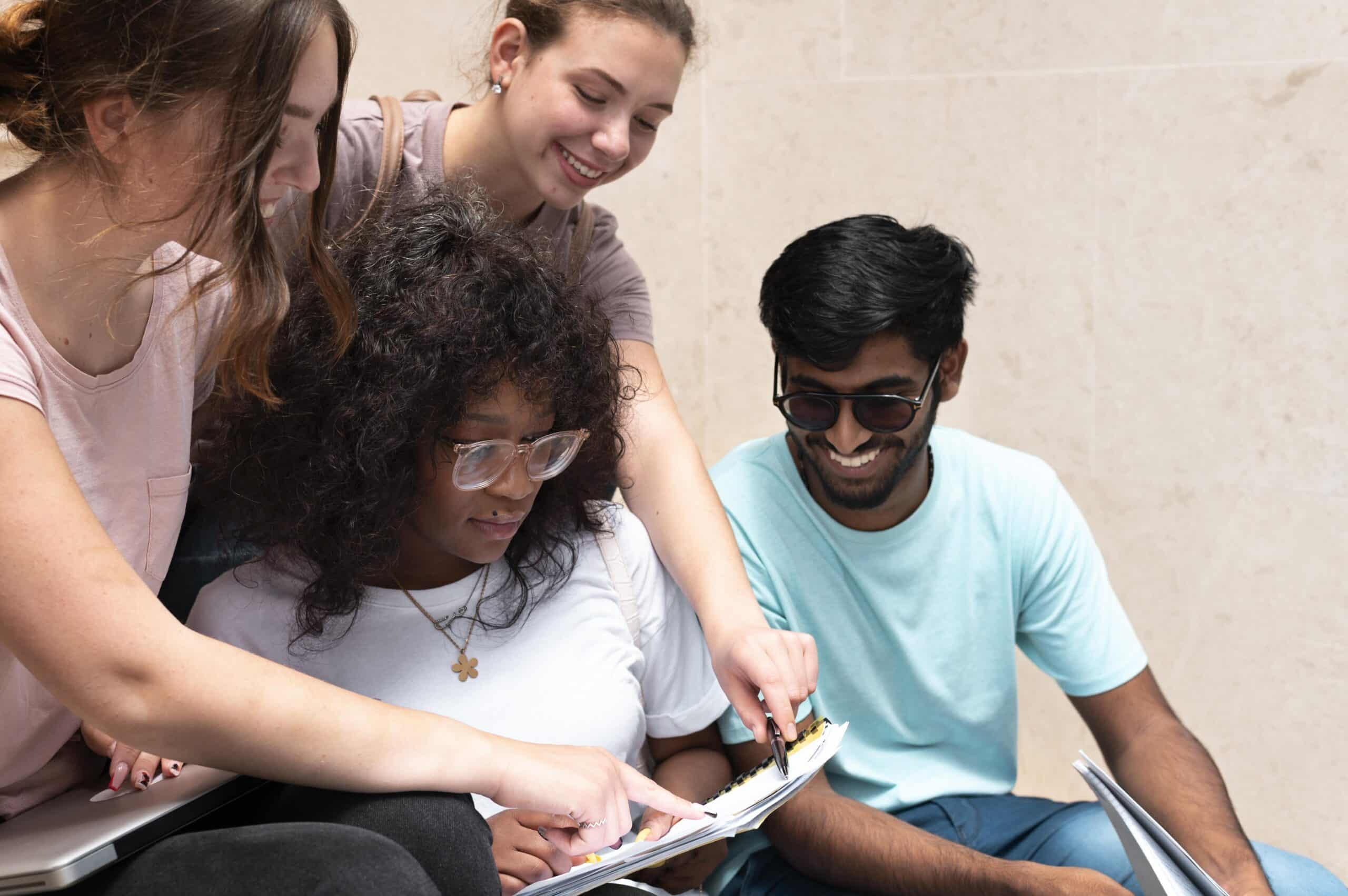 Jovens sentados em círculo analisam anotações e sorriem juntos