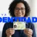 Mulher segura cartão do novo RG com sorriso em ambiente doméstico iluminado