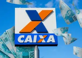 Placa da Caixa Econômica Federal com notas de R$ 100 voando ao redor em céu azul