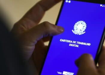 Pessoa usando celular com tela exibindo aplicativo Carteira de Trabalho Digital