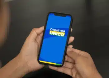 Mãos segurando celular com aplicativo do Cadastro Único na tela