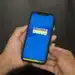 Mãos segurando celular com aplicativo do Cadastro Único na tela