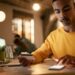 Homem com cartão de crédito usando smartphone ao lado de notebook em ambiente interno