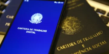 Carteira de Trabalho física e digital ao lado de teclado, representando o prazo de pagamento do salário no 5º dia útil de maio de 2026