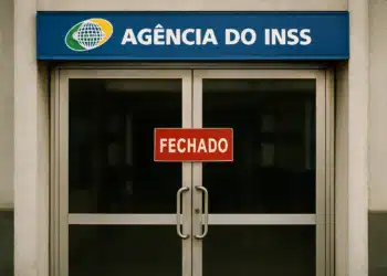 Agência do INSS fechada com placa vermelha na porta de vidro.