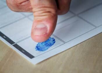 Coleta de impressão digital em ficha datiloscópica oficial.