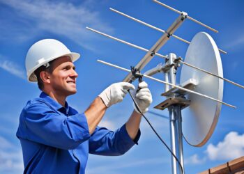 Técnico ajusta antena parabólica no telhado.