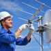 Técnico ajusta antena parabólica no telhado.