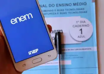 Celular exibe aplicativo oficial do ENEM com caderno azul ao fundo.