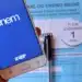 Celular exibe aplicativo oficial do ENEM com caderno azul ao fundo.