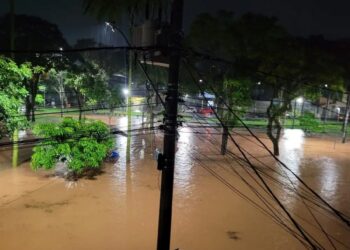 Rua alagada após chuvas intensas, mostrando áreas afetadas pela enchente.