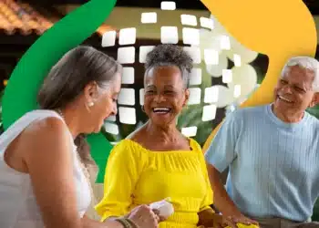 Três pessoas idosas sorrindo sentadas, fundo com elementos gráficos verde e amarelo, simbolizando o pagamento do 13º salário do INSS.