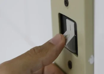 Mão aciona interruptor de luz, representando o acesso ao desconto na tarifa de energia elétrica pelo programa "Luz do Povo" em 2026