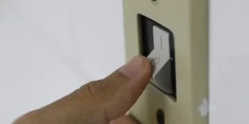 Mão aciona interruptor de luz, representando o acesso ao desconto na tarifa de energia elétrica pelo programa "Luz do Povo" em 2026