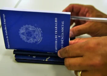 Mãos segurando carteira de trabalho e previdência social, representando as mudanças trabalhistas trazidas pela nova lei de licença-paternidade de 2026
