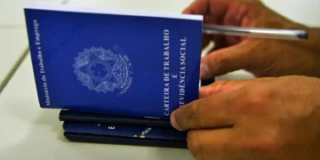 Mãos segurando carteira de trabalho e previdência social, representando as mudanças trabalhistas trazidas pela nova lei de licença-paternidade de 2026