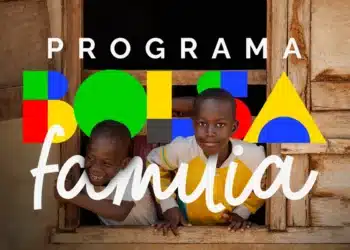 Duas crianças negras sorriem apoiadas em uma janela de madeira, com a logomarca colorida do Programa Bolsa Família sobreposta à imagem.