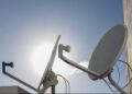 Antenas parabólicas instaladas em telhado com céu azul ao fundo