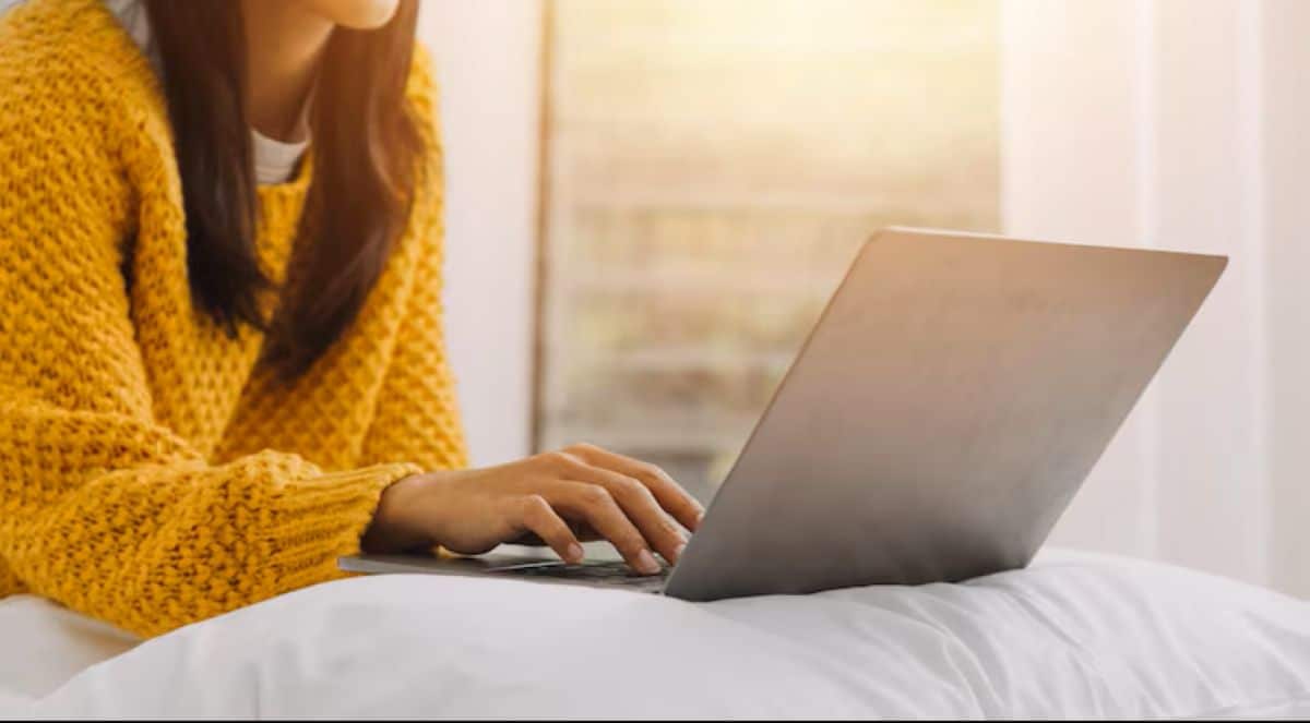 Pessoa deitada utilizando notebook e tablet