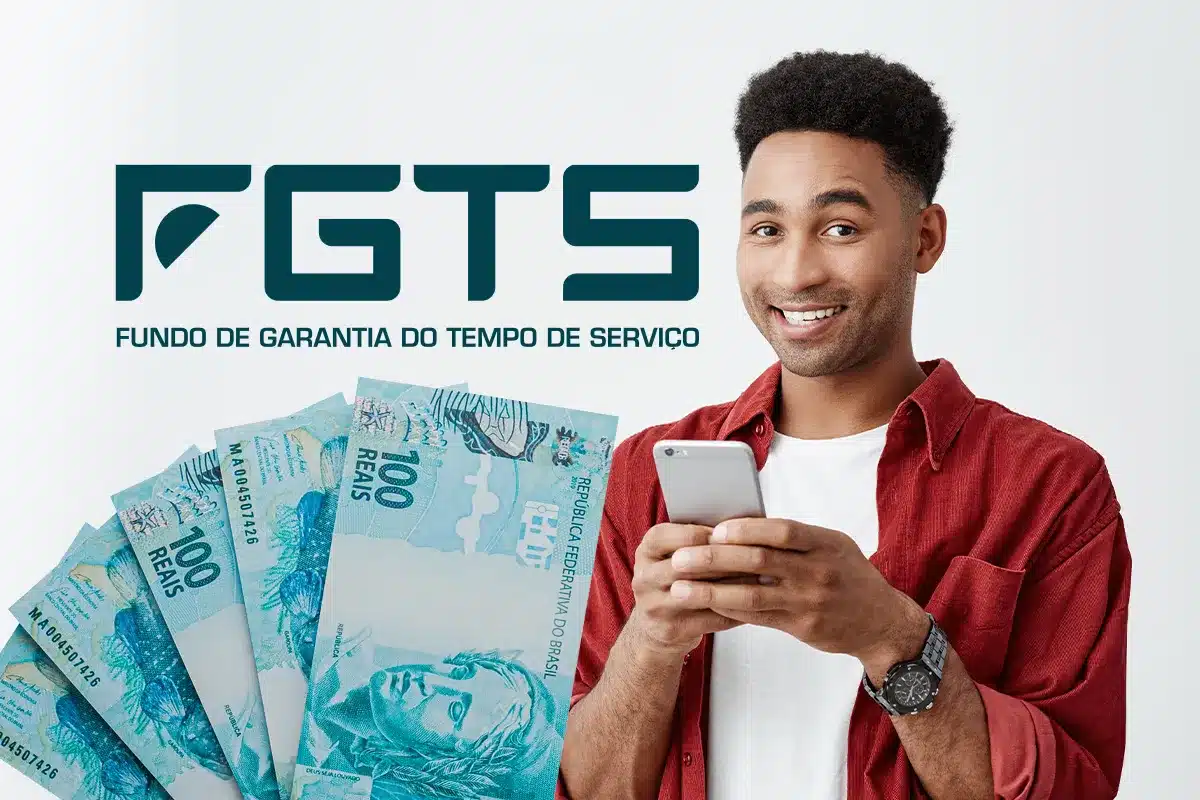 FGTS: Passo a passo para conferir o saldo na conta Homem segurando celular ao lado da logo do FGTS e notas de cem reais